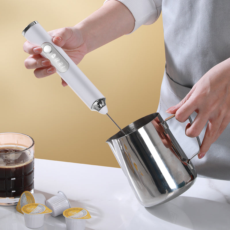 Using a cordless rechargeable milk frother in a stainless steel frothing pitcher.